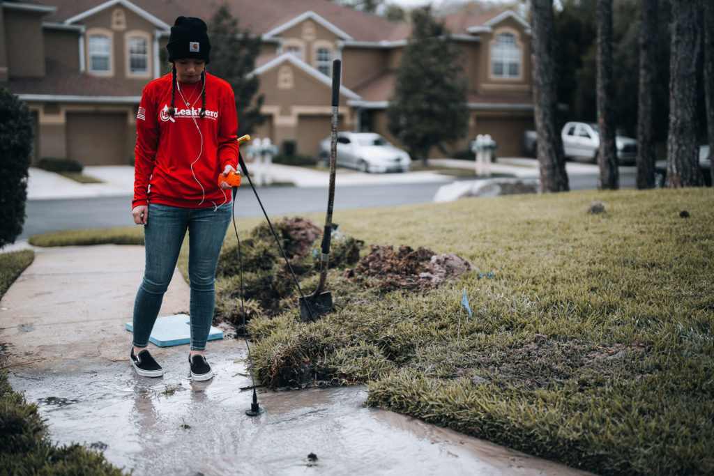 Woman conducting sonar leak detection in a driveway.