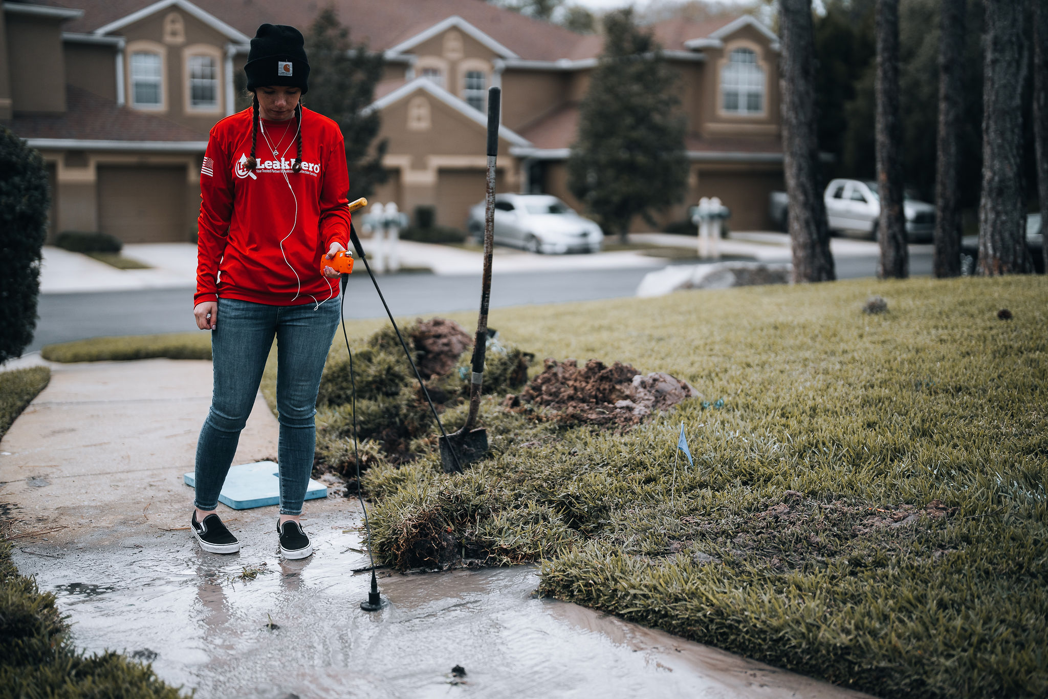 Woman conducting sonar leak detection in a driveway. 